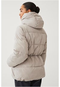 Giacca puffer beige chiaro con cappuccio, caratterizzata da sezioni trapuntate, vita arricciata e texture liscia e lucida.