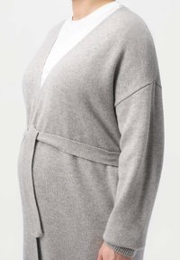 Grå stickad kardiagan med djup V-hals, vida ärmar och ett knytbälte i midjan. Mjuk textur med en slät yta.