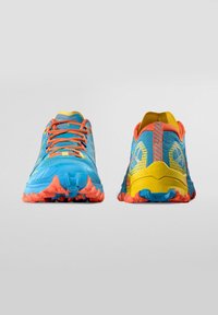 Modré a žluté běžecké boty mají texturovaný svršek, oranžové šněrování a vícolorovou gumovou podrážku s výraznými vzory pro zvýšenou trakci.
