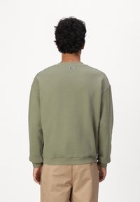 Oliwkowa bluza z okrągłym dekoltem i ściągaczami, z małym logo z tyłu, luźny krój i gładka bawełniana tekstura.