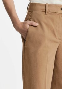 Jasnobrązowe, wysokie spodnie o prostym kroju, z bocznymi kieszeniami i gładką fakturą, wykonane z miękkiej mieszanki tkanin.