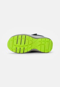 Grau- und grüner Schuhsohle mit athletischem Design, die eine strukturierte, gemusterte Oberfläche mit einem auffälligen Zickzack-Griffmuster aufweist. Markenname "superfit" sichtbar.