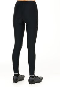 Black cycling tights, made of stretchy material, feature a fitted design with a padded seat area and reflective accents near the ankles.