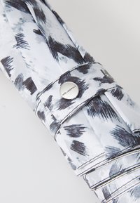 Folded umbrella featuring a gray and black brushstroke pattern on a white background, secured with a metallic snap and detailed stitching.