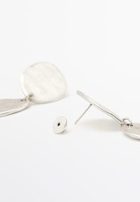 Zilveren oorbellen met een getextureerd, cirkelvormig ontwerp en een bevestigd ovaal stukje. Inclusief een kleine bevestigingspost voor een veilige sluiting.