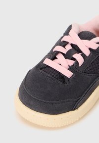 Mørkegrå semsket sneaker med rosa lisser, mesh-detaljer og en kremfarget gummisåle med et strukturert mønster nær bunnen.