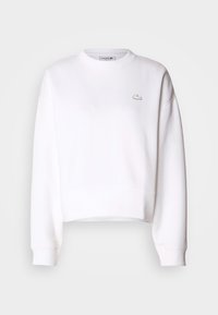 White cropped sweatshirt, cotton blend, crew neckline, long sleeves, ribbed cuffs, featuring a small Lacoste logo on the chest.