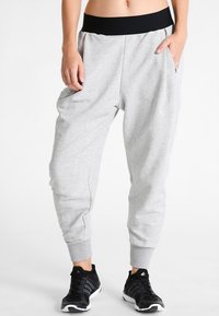 Grijze sweatpants met een visgraatpatroon, zwarte tailleband en afgeknipte enkels. Heeft zijzakken en een ontspannen pasvorm.