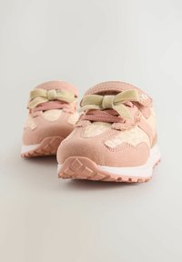 Rosa träningsskor med en texturerad mockaovandel, nätinslag, en rosett och en robust gummisul för bra grepp.