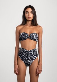 Costume da bagno a bandeau in stampa leopardata bianca e nera, caratterizzato da un top con arricciature e un fondo a vita alta con lati arricciati e un design senza cuciture.