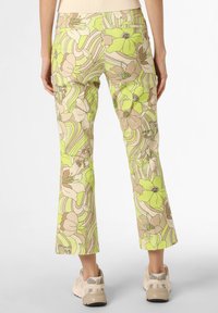 Uppvikta byxor i lätt material med ett blommönster i pastellgrön och beige ton, accentuerat med vågiga mönster och bakfickor.