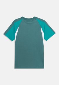Camiseta de manga corta en color azul verdoso con detalles en blanco y gris oscuro. Fabricada en suave algodón, presenta un cuello redondo y mangas raglán en contraste.