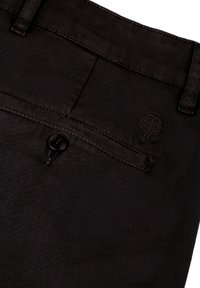 Zwarte denim broek met een achterzak met knoopsluiting en een geborduurd boomlogo. GLadde textuur met fijne stikdetails.