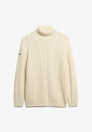 Pull en tricot de couleur crème avec col roulé, motif en côtes, poignets et ourlet côtelés, et un détail de logo sur une manche.
