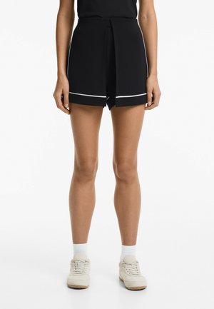 Black shorts with a wrap design, featuring a white trim along the hem. Made of lightweight fabric, styled with a relaxed fit.