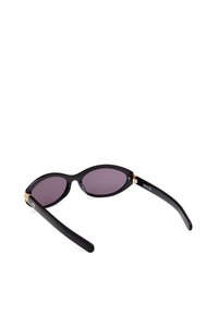 Zwarte zonnebril met ovale getinte lenzen en gouden accenten bij de scharnieren. Strak ontwerp met dikke zwarte steunen en een gladde afwerking.