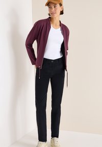 Burgundy zip-up jacka, vit t-shirt, svarta byxor och beige sneakers. Slät tygtextur med en avslappnad passform och minimal detaljering.