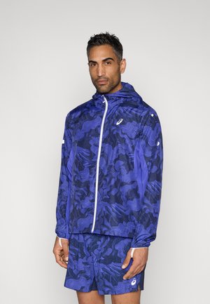 Veste de sport violette avec un motif ondulé, fermeture éclair et capuche. Associée à un short assorti, les deux ont une texture lisse et un tissu évacuant l'humidité.