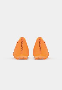 Botas de fútbol de color naranja brillante con una parte superior de malla texturizada, puntera redondeada y un prominente logotipo "ULTRA" en el talón. Suela de goma con tacos.