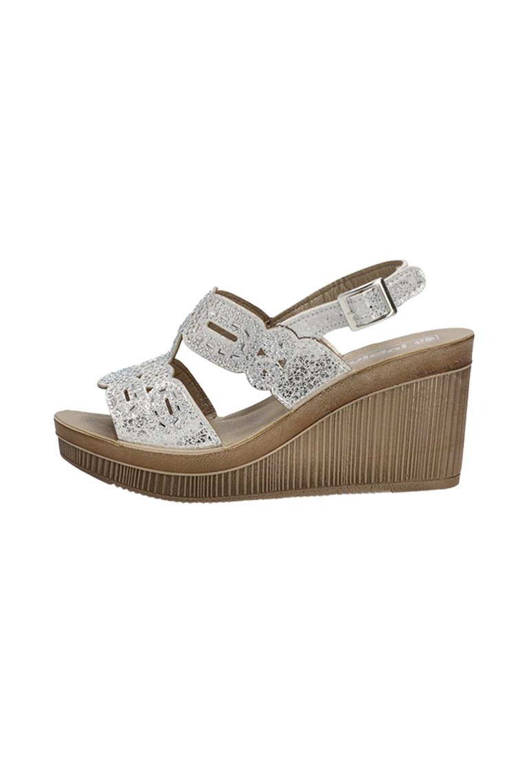 Sandalias de cuña con una parte superior brillante blanca, diseño de punta abierta, correa ajustable en el tobillo y suela de plataforma texturizada marrón.