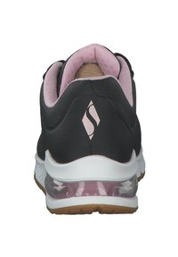 Czarne buty sportowe z różowymi akcentami i wyściełanym kołnierzem, z teksturowaną cholewką, przezroczystą piętą i białą gumową podeszwą.