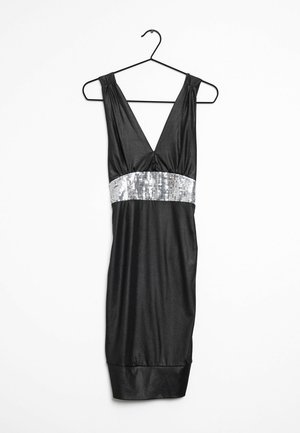 Robe noire sans manches avec un col en V profond et une large ceinture argentée à sequins, suspendue à un cintre noir sur fond blanc.