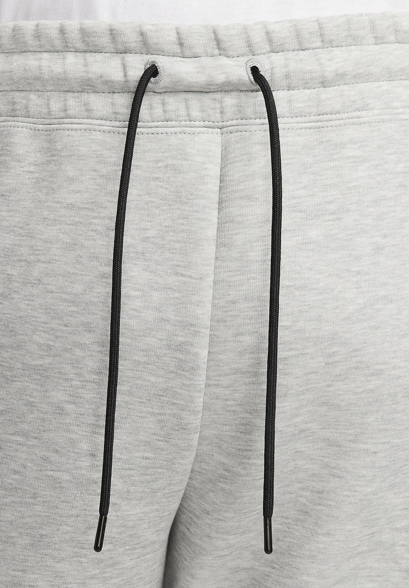Helle graue Sweatpants mit strukturierter Oberfläche, ausgestattet mit einem schwarzen Kordelzug mit silbernen Enden und einem elastischen Bund.