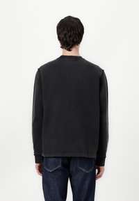 Kulgrå sweatshirt med rund hals og lange ærmer. Har en afslappet pasform og en blød tekstur. Bæret med blå denimjeans.