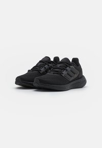 Scarpe da ginnastica nere realizzate in rete e materiali sintetici, con suola texture, chiusura con lacci e design a tre strisce sui lati.