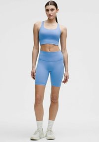 Ljusblå sportbh och matchande högmidjade cykelshorts, tillverkade av ett smidigt, stretchigt material, utformat för atletisk klädsel.