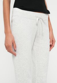 Ανοιχτό γκρι παντελόνι φόρμας από μαλακό βαμβακερό μείγμα, με ελαστική μέση, κορδόνι και λεπτομέρειες στην πλαϊνή ραφή.