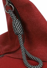 Tessuto rosso con una superficie liscia, dotato di una cerniera e di un cordone a motivi bianco e nero attaccato a un anello di metallo.