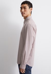 Camicia a maniche lunghe a righe marroni chiari e bianche, con colletto button-down e polsini decorati con bottoni. Tessuto dalla consistenza liscia.