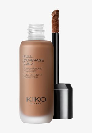 Flaschen mit Foundation und Concealer, beschriftet mit "Full Coverage 2-in-1", und Applikatorstab, getaucht in mittelbraunen Make-up.