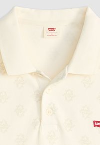 Levi's Polo-Shirt in Standard Fit in Creme, mit weichem Stoff, subtilm Musterdesign, drei Knöpfen und einem Markenlabel am Kragen.