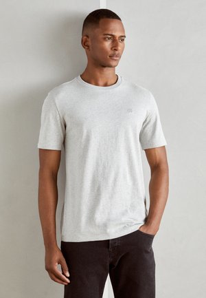 Gray short-sleeve T-shirt made of soft fabric with a round neckline and subtle logo detail on the chest, paired with dark pants.