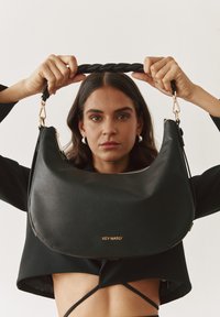 Sac à bandoulière en cuir noir avec une finition texturée, une bandoulière tressée et un logo doré "HEY MARLY" à l'avant, doté d'une fermeture éclair.