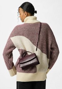 Overdimensioneret sweater med et mønster i creme og burgunder, sammen med en lille burgunder taske i kunstlæder med en struktureret finish.