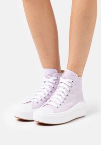 High-top sneakers in light lavender canvas with white laces and rubber sole; features silver eyelets and textured white platform.