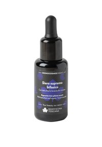Bottiglia contagocce in vetro nero con forma arrotondata. Presenta un'etichetta blu e bianca con testo e accenti floreali. Contiene un siero bifasico.