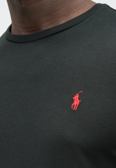 Sötétzöld, pamutkeverék anyagú póló, környakú, bal mellrészen kis piros hímzett pólójátékos logóval.