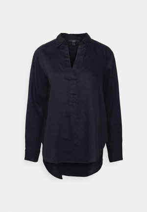 Blouse en lin noir à manches longues avec col et encolure en V, ourlet arrondi plus long à l'arrière, poignets boutonnés, coupe ample.
