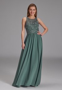 Langes grünes Kleid mit einem strukturierten Spitzen-Oberteil und fließendem Rock. Hat einen hohen Kragen und ein ärmelloses Design. Glatte Stofftextur.