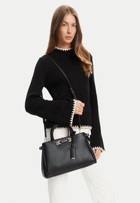 Borsa a mano nera strutturata con doppio manico superiore, tracolla regolabile, accessori in oro e etichetta staccabile. Texture in pelle liscia.