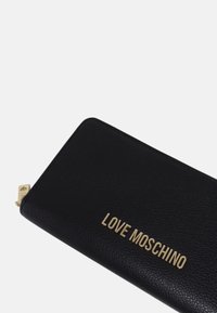 Black leather wallet with a textured finish and gold "LOVE MOSCHINO" logo. Features a zip closure and sleek rectangular shape.
