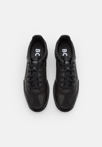 Baskets noires avec une tige en cuir lisse ornée d'accents perforés, bout rond, design à lacets et semelle en caoutchouc avec un marquage discret.