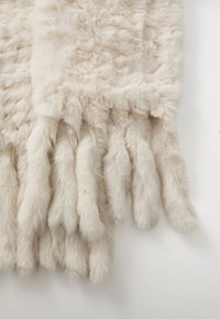 Gants en fausse fourrure d'une douce couleur beige clair, présentant une surface texturée et duveteuse ainsi qu'une forme de doigts allongés de longueur uniforme.
