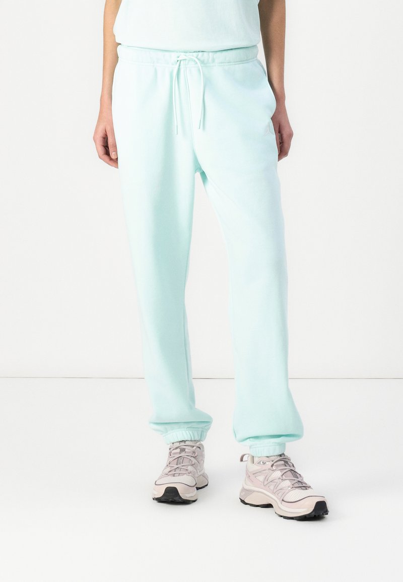 Licht mintgroene sweatpants met een trekkoord in de taille, ribbelmanchetten en een zachte textuur, gecombineerd met grijze en zwarte sport schoenen.