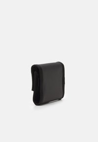 Kompakt svart lommebok laget av glatt lær, med en fold-over design og kontrasterende sømmer. Minimalistisk og rektangulær form.