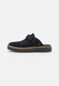 Scarpa slip-on nera in suede con suola platform spessa, dotata di una singola cinghia e una fibbia. Accentuata da cuciture gialle lungo la suola.